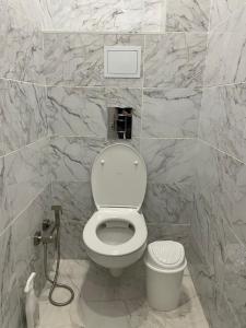 a bathroom with a white toilet and marble walls at 1 комн квартира in Oral