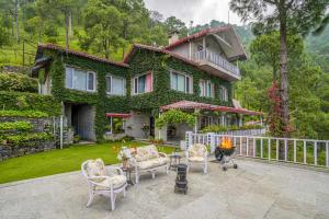 a green house with chairs and a table in front of it at StayVista at Destine in Kasauli
