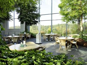 un restaurante con mesas, sillas y ventanas grandes en Seminarhotel in der Manfred-Sauer-Stiftung, en Lobbach