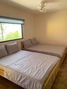 2 camas en una habitación con ventana en Nhà Nghỉ Ngọc Ánh, en Ấp Tam Tân