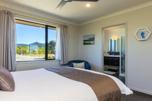 a bedroom with a large bed and a large window at Ocean View Beachfront Apartment in Blenheim