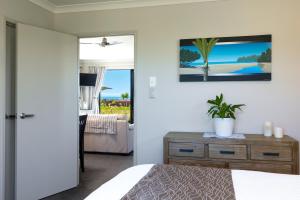 ein Schlafzimmer mit einem Bett und eine Kommode mit einer Pflanze darauf in der Unterkunft Ocean View Beachfront Apartment in Blenheim