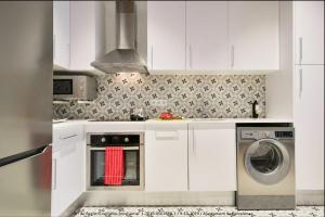 a kitchen with white cabinets and a washer and dryer at Design Apartments Plaza Catalunya in Barcelona