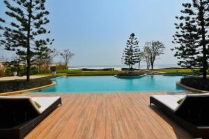 une piscine avec deux chaises longues et des arbres dans l'établissement Tascany Sea Beach Chaam-Huahin, à Cha Am 35 autres photos