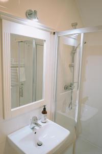 a white bathroom with a sink and a shower at Karczma Viking in Stara Kiszewa