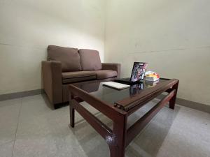 ein Wohnzimmer mit einem Sofa und einem Tisch mit einem Laptop in der Unterkunft SPOT ON 92338 Karin Kost in Banjarbaru
