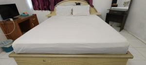 ein weißes Bett in einem Zimmer mit einem TV in der Unterkunft SPOT ON 92338 Karin Kost in Banjarbaru