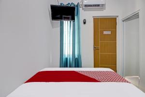 a bedroom with a bed with a red blanket and a door at Super OYO Collection O 92363 Kp Inn in Yogyakarta