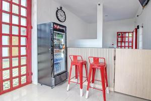Super OYO Collection O 92363 Kp Inn في يوغياكارتا: مطبخ مع اثنين من الكراسي الحمراء وثلاجة