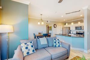 sala de estar con sofá azul y cocina en Whitecap Retreat en Padre Island