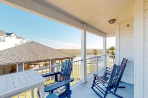 two blue chairs on a porch with a view of the ocean at Whitecap Retreat in Padre Island
