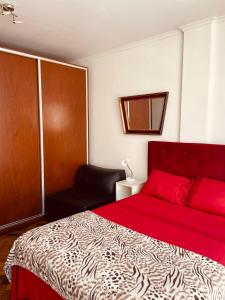 1 dormitorio con 1 cama roja y 1 silla en Departamento en el Casco Histórico de la ciudad de Buenos Aires en Buenos Aires