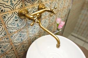 a toilet with a gold handle on a wall at Villabaroque_Eger in Eger