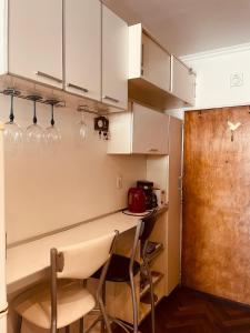 una cocina con armarios blancos y una barra con sillas en Departamento en el Casco Histórico de la ciudad de Buenos Aires en Buenos Aires