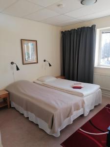 Schlafzimmer mit einem großen weißen Bett und einem Fenster in der Unterkunft Hotell Hemgården in Bengtsfors