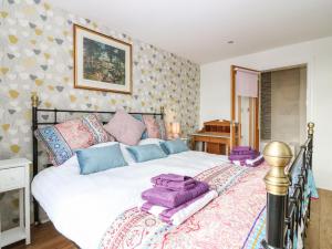a bedroom with a large bed with purple pillows on it at Beach Cottage in Kinghorn