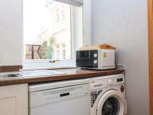 a kitchen with a microwave and a washing machine at Beach Cottage in Kinghorn