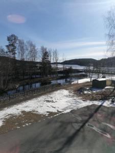 een weg met sneeuw op de grond naast een rivier bij Hotell Hemgården in Bengtsfors