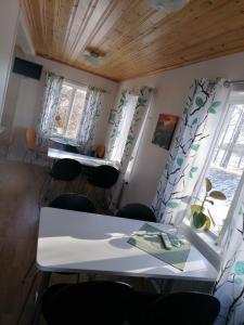 a room with a table and chairs and two windows at Hotell Hemgården in Bengtsfors