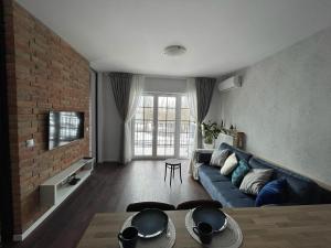 a living room with a blue couch and a brick wall at Niezapominajka przy Manufakturze in Łódź