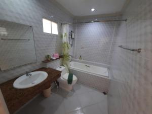 a bathroom with a sink and a toilet and a tub at Fancy Carp Resort in Cha Am
