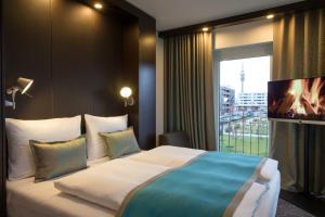 uma cama grande num quarto de hotel com uma janela em Motel One München-Olympia Gate em Munique