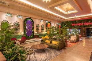a lobby with chairs and tables and plants at Megasaray Westbeach Antalya in Antalya