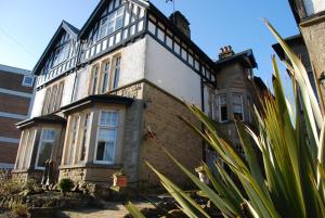 an old brick house with white windows and plants at Springdale Guest House in Harrogate