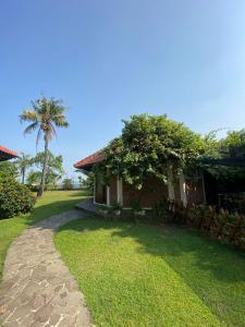 una casa con una palmera y un camino en Jepara Marina Beach Bungalows, en Jepara