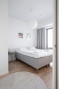 a white bedroom with a bed and a window at 2ndhomes Tampere Brand New "Station" Apartment with Sauna in Tampere