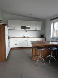 西海姆的住宿－Apartment im Salzburger Seenland，厨房配有白色橱柜、木桌和凳子