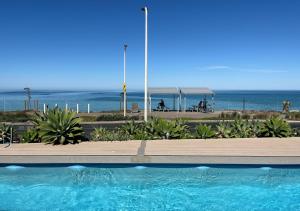 a swimming pool with the ocean in the background at Glenelg Beach House With Private Beachfront Pool in Glenelg