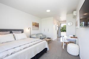 a white bedroom with a bed and a desk and a table at Views over Tasman, New luxury boutique studio overlooking the Tasman Sea in Greymouth