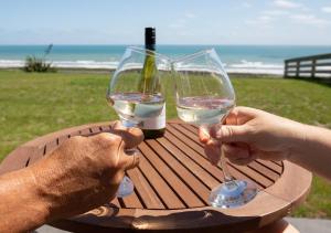 two people are holding glasses of white wine at a table at Views over Tasman, New luxury boutique studio overlooking the Tasman Sea in Greymouth