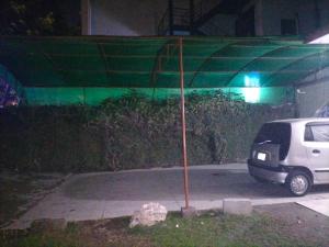 a white van parked under a green canopy at night at Kingston Motel in Lahore