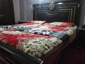 a bed with a red and white blanket and pillows on it at Kingston Motel in Lahore
