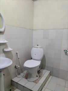 a white bathroom with a toilet and a sink at Kingston Motel in Lahore