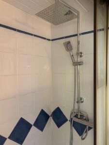 y baño con ducha y azulejos azules y blancos. en Les clapiers appartement avec jacuzzi et rivière., en Mialet
