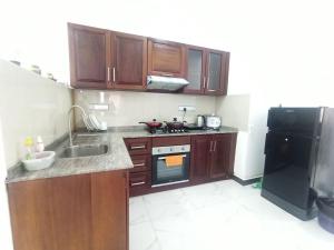 a kitchen with wooden cabinets and a black refrigerator at 3 bedroom fully furnished apartment - Vel residencies in Colombo
