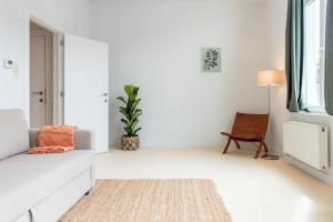 a white living room with a couch and a chair at Lichtrijk appartement op toplocatie in Gent in Ghent