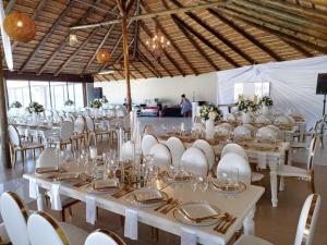 a banquet hall with white tables and white chairs at Coastal Beach Resort in Umkomaas