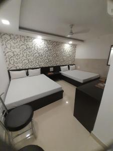 希萨尔Hotel Shree的有两张床和一把椅子的房间
