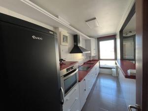 a kitchen with white cabinets and a black refrigerator at Duplex Bahía de Santoña in Santoña