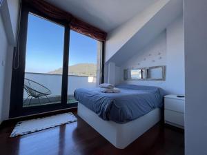 um quarto com uma cama e uma grande janela em Duplex Bahía de Santoña em Santoña