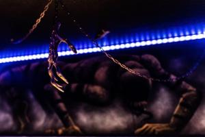 una persona se aferra a una cadena con una luz azul en Le Cirque Ensorcelé - Le Studio Maudit & Cosy en Belfort