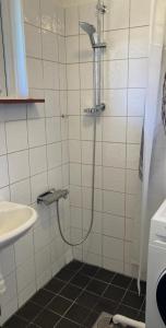 a shower in a white tiled bathroom with a sink at Blå Dörren in Höör