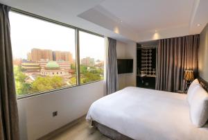 a hotel room with a bed and a large window at CHECK inn Taipei Main Station in Taipei