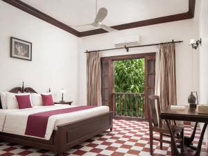 a bedroom with a bed and a desk and a window at Chateau d'Angkor La Residence in Siem Reap