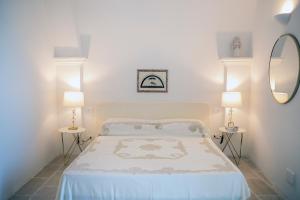 1 dormitorio con 1 cama con 2 lámparas y espejo en dimore di portadibasso en Peschici