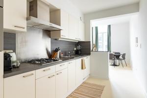 La cuisine est équipée de placards blancs et d'un four avec plaques de cuisson. dans l'établissement Lichtrijk appartement op toplocatie in Gent, à Gand